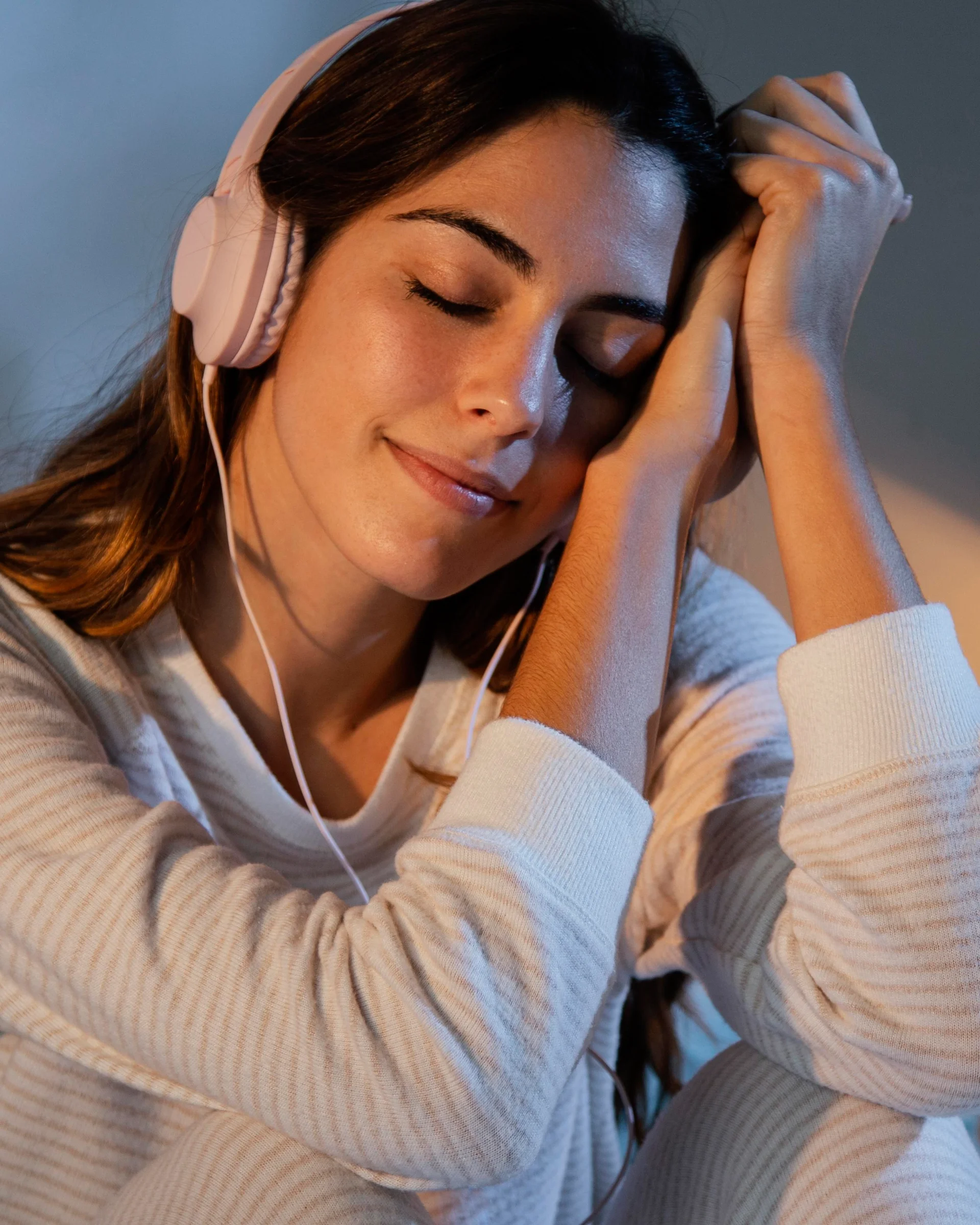 woman-using-headphones-music-home-bed