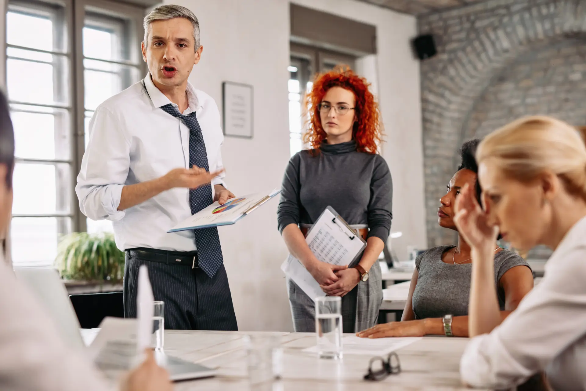 angry-businessman-feeling-disappointed-with-business-reports-scolding-his-team-during-meeting-office